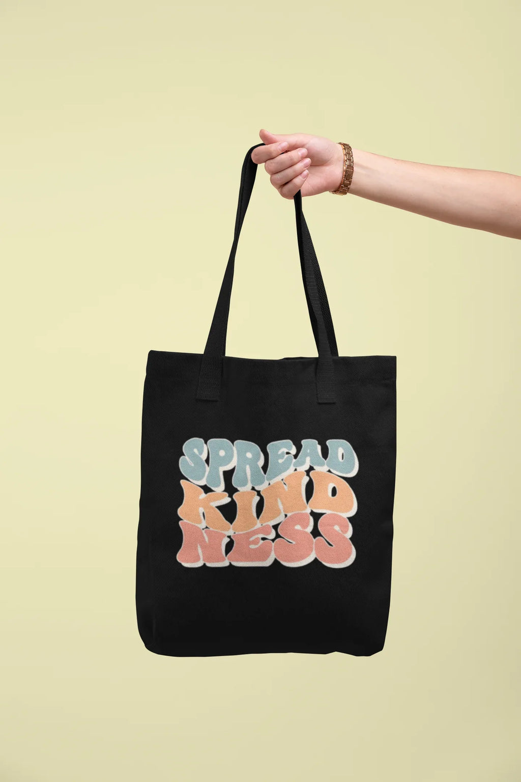 Black cotton tote bag with 'SPREAD KINDNESS' graphic, held by a hand
