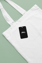 White canvas tote bag with black hanging tag reading Alley.