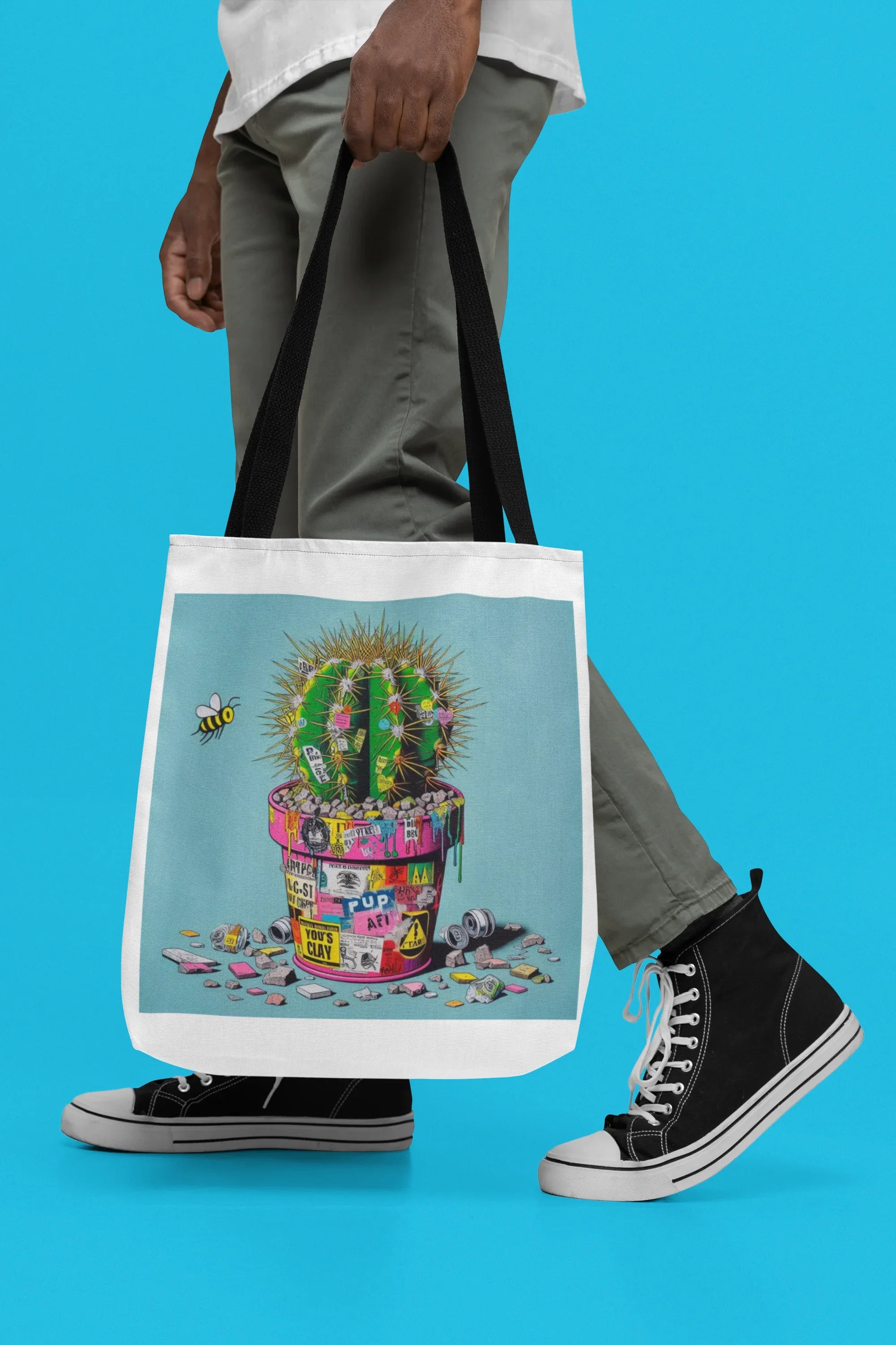 Tote bag with cactus artwork, light blue panel, black handles hanging in front