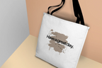 White canvas tote bag with black handles, side view of “Have a great day.” splash