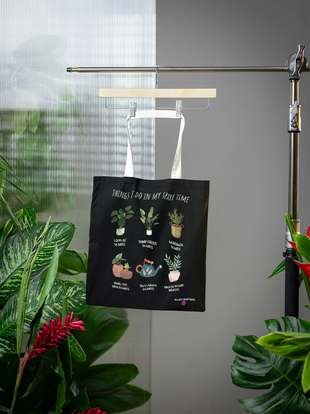 Black tote bag with plant illustration graphic and phrase, hanging