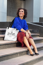White canvas tote bag with top handles and printed slogan, resting on steps