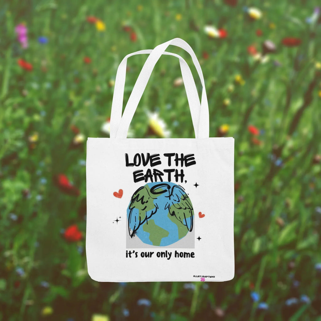 White tote bag with “Love the Earth” text and globe illustration in garden