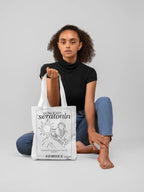 White canvas tote bag on display with black front graphic and handles