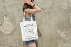 White tote bag hanging from shoulder straps with black line drawing front panel