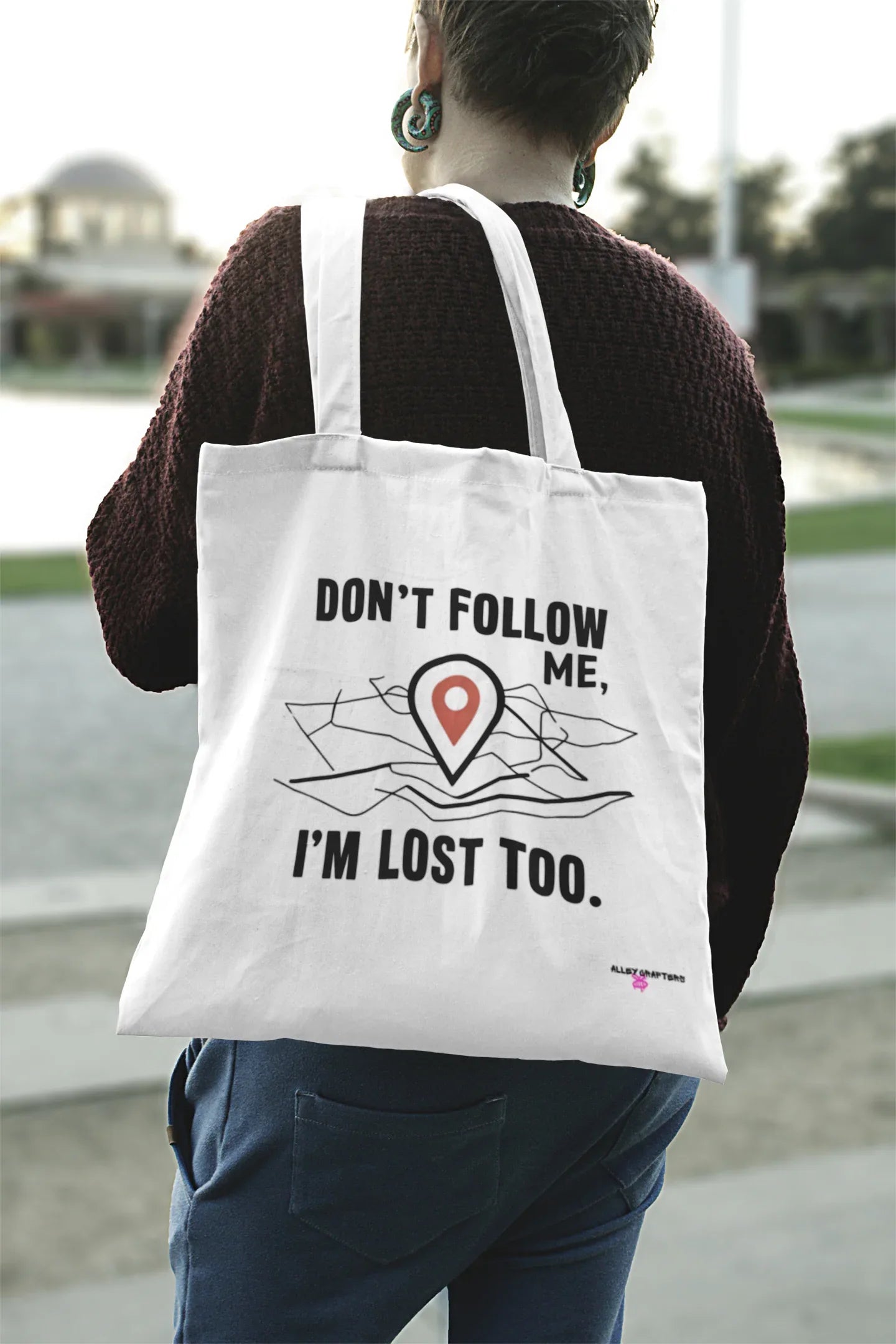 White canvas tote bag with black "DON'T FOLLOW ME" and "I'M LOST TOO" map-pin