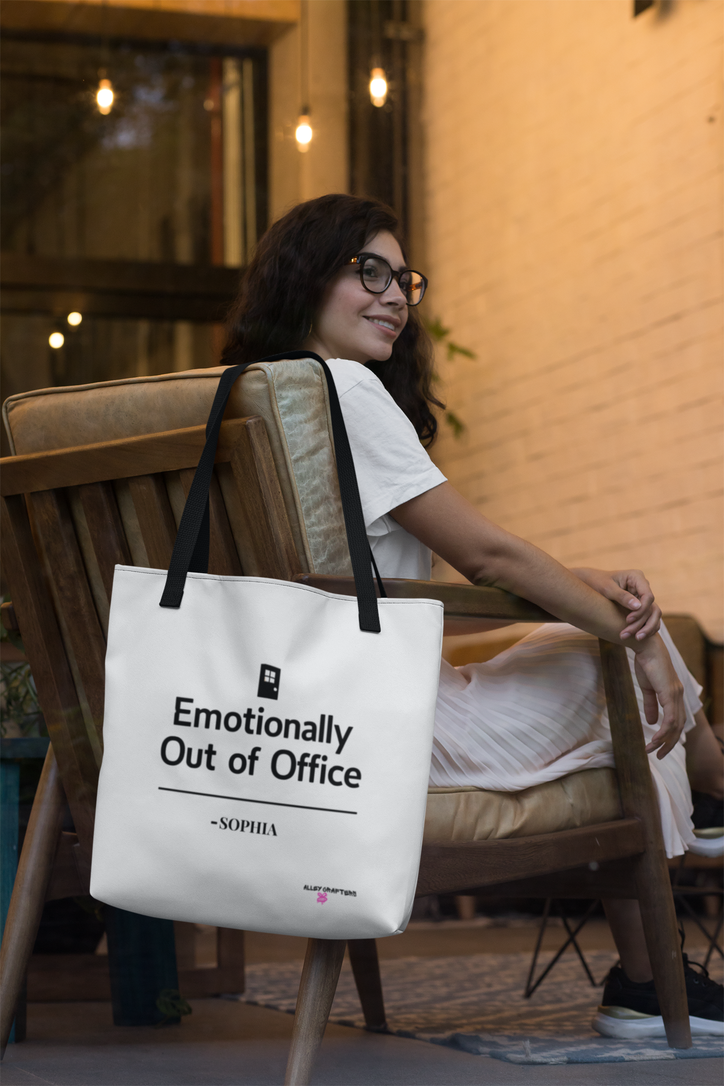 White tote bag with black handles and 'Emotionally Out of Office' print.