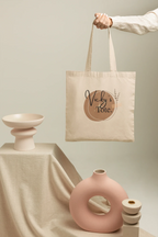 Light canvas tote bag held by rope handles with Vicky's Tote round logo