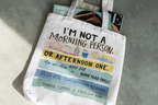 White tote bag with 'I'm not a morning person' slogan and colorful band print