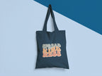Dark gray cotton tote bag with 'SPREAD KINDNESS' graphic on the front