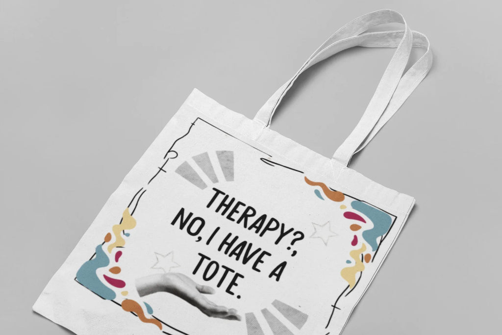 White tote bag with printed quote and colorful border, shown from above with handles.