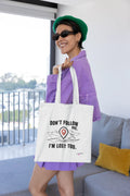 White canvas tote bag with black "DON'T FOLLOW ME" text and red location-pin graphic