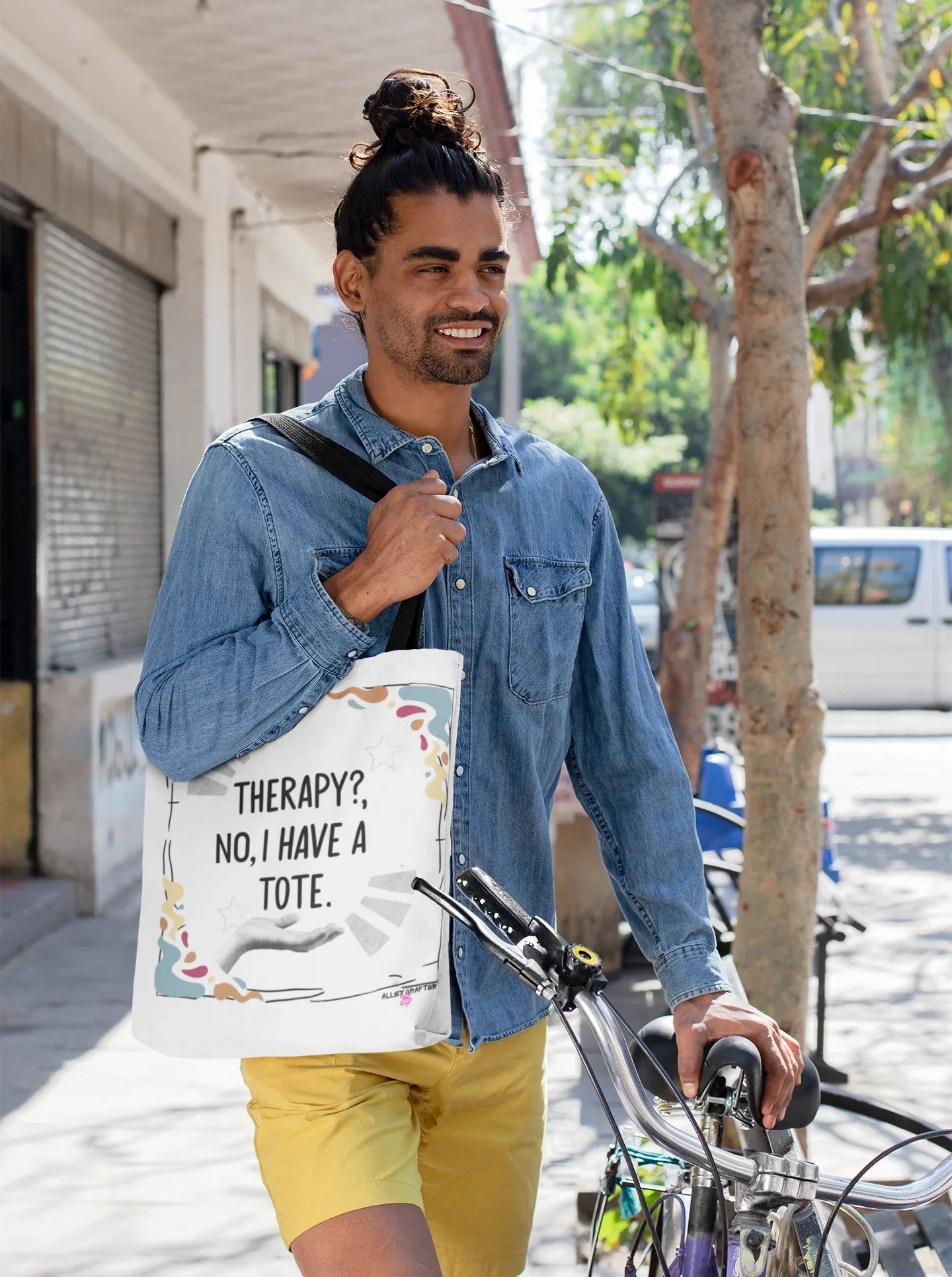 White tote bag with printed quote and colorful doodles, carried outdoors on a bicycle.