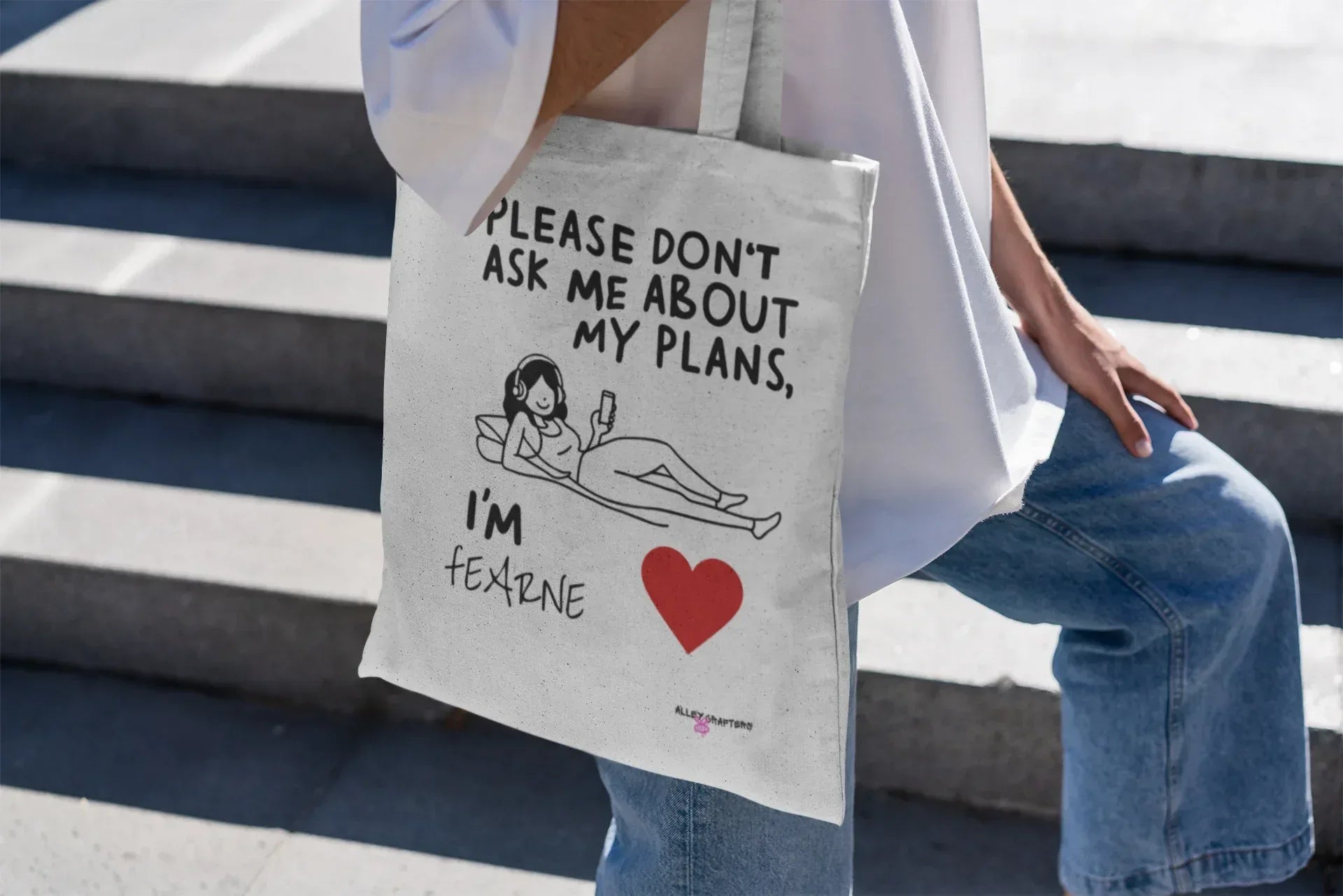 White canvas tote bag with bold quote, “Please don’t ask me about my plans,” and red heart