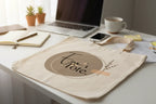 Cream cotton tote bag lying on desk with circular 'Tote.' logo print