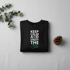 Black crewneck sweatshirt folded flat with “Keep Calm and Enjoy the waves” front design.