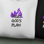Close-up of white hoodie chest print: purple flames graphic with “TRUST GOD’S PLAN”.