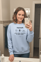 Light blue personalized crewneck sweatshirt with name Hannah and coffee, trees, mountains