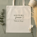 White cotton tote bag with centered “SISTERS forever” script and names