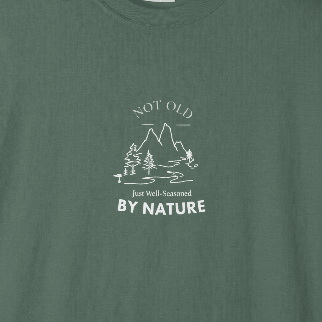 Dark green T-shirt with white mountain and tree graphic, 'By Nature' text