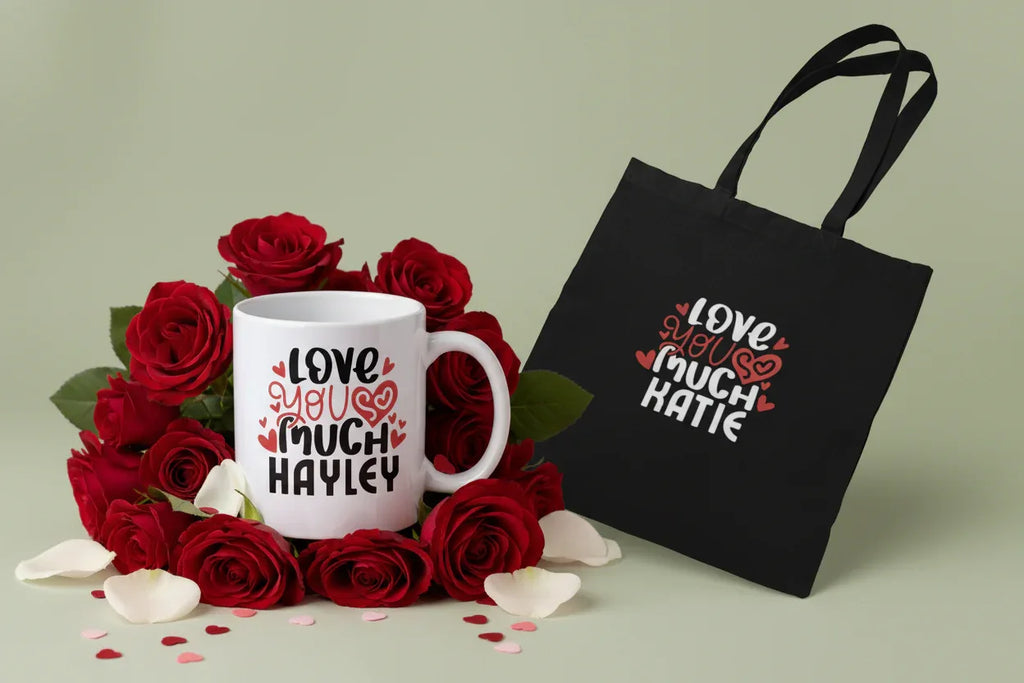 White mug with "Love You So Much" personalized text beside black tote bag with matching print