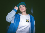 White crewneck sweatshirt with flower smiley patch on chest, worn with denim.