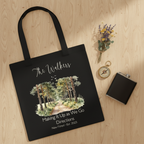 Black tote bag, front view, with watercolor forest illustration and printed text