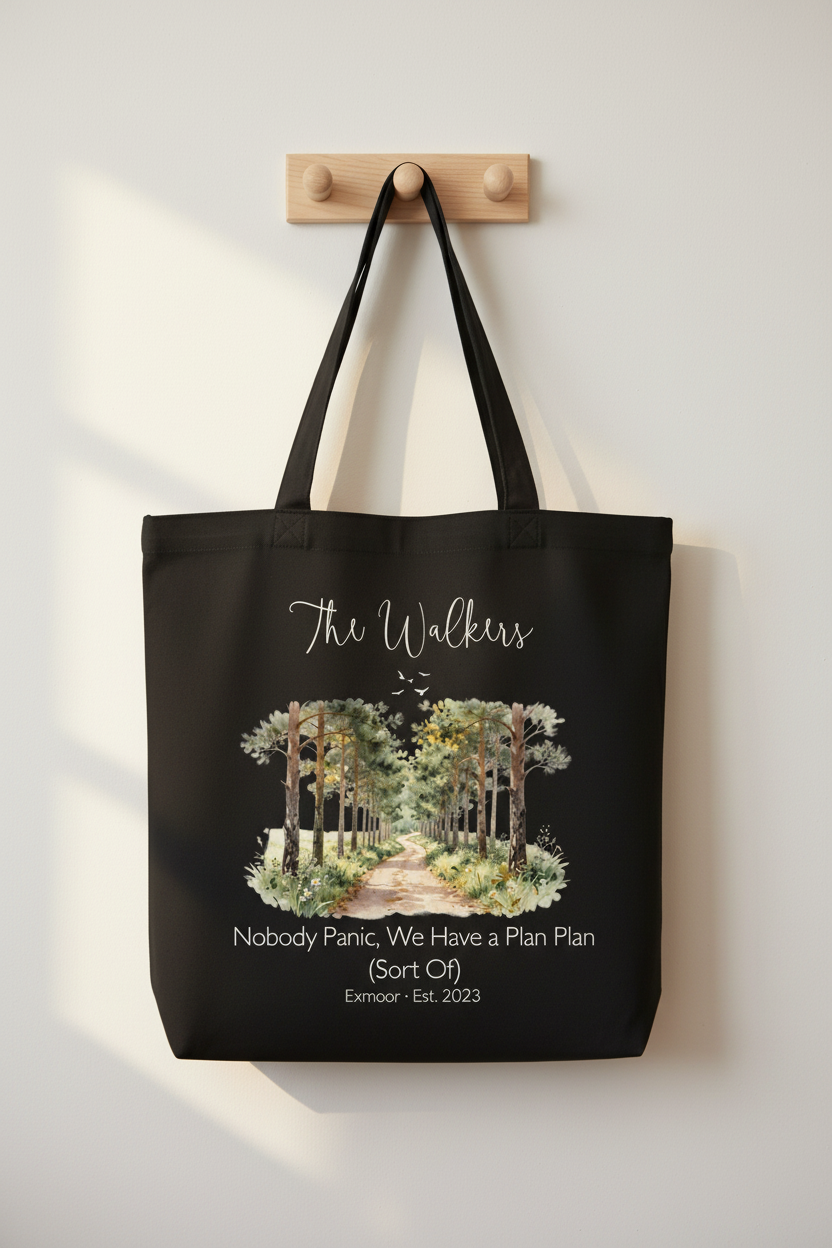 Black tote bag with watercolor forest graphic and script family name