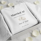 White couples hoodie in a box with “Married AF” text, ring graphic, and names