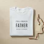 White folded dad T-shirt with 'I'M A PROUD FATHER' and child names, hanging tag