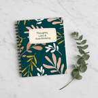 A5 spiral notebook with teal botanical cover and centered beige label reading “Thoughts, Lists & Overthinking”.