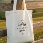 White cotton tote bag with mountain sketch, 'adventure awaits' text and pink heart