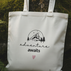 White cotton tote bag front panel with mountain sketch, 'adventure awaits' and heart