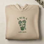 Light stone pullover hoodie with EMMA palm plant graphic and “wild inside” text.