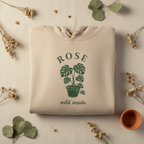 Light cream pullover hoodie with ROSE palm plant graphic and “wild inside” text.