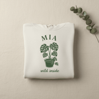 White pullover hoodie with MIA palm plant graphic and “wild inside” text.