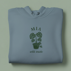Light blue hoodie with front hood and eyelet drawstrings; potted palm graphic with “MIA”.