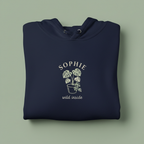 Navy hoodie with front hood and eyelet drawstrings; palm graphic with “SOPHIE” text.