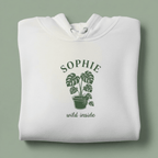 White hoodie with front hood and eyelet drawstrings; potted palm graphic with “SOPHIE”.