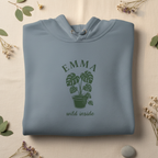 Powder blue pullover hoodie with EMMA palm plant graphic and “wild inside” text.