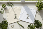 Two crew-neck T-shirts, cream and white, each with “Slow Progress” plant graphic