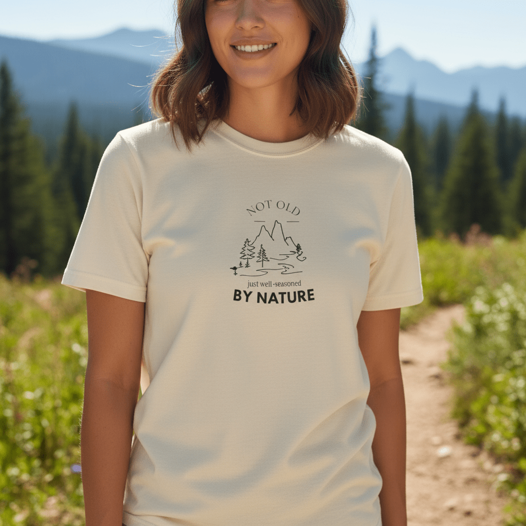 Cream/ivory graphic T-shirt with mountain and trees logo and “BY NATURE” chest print
