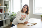 White crewneck sweatshirt featuring a floral inspirational text graphic on chest