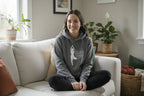 Gray pullover hoodie with hood and front pocket, featuring dancer silhouette logo graphic