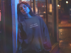 Dark crewneck sweatshirt with 'a year wiser, a world kinder' text on chest